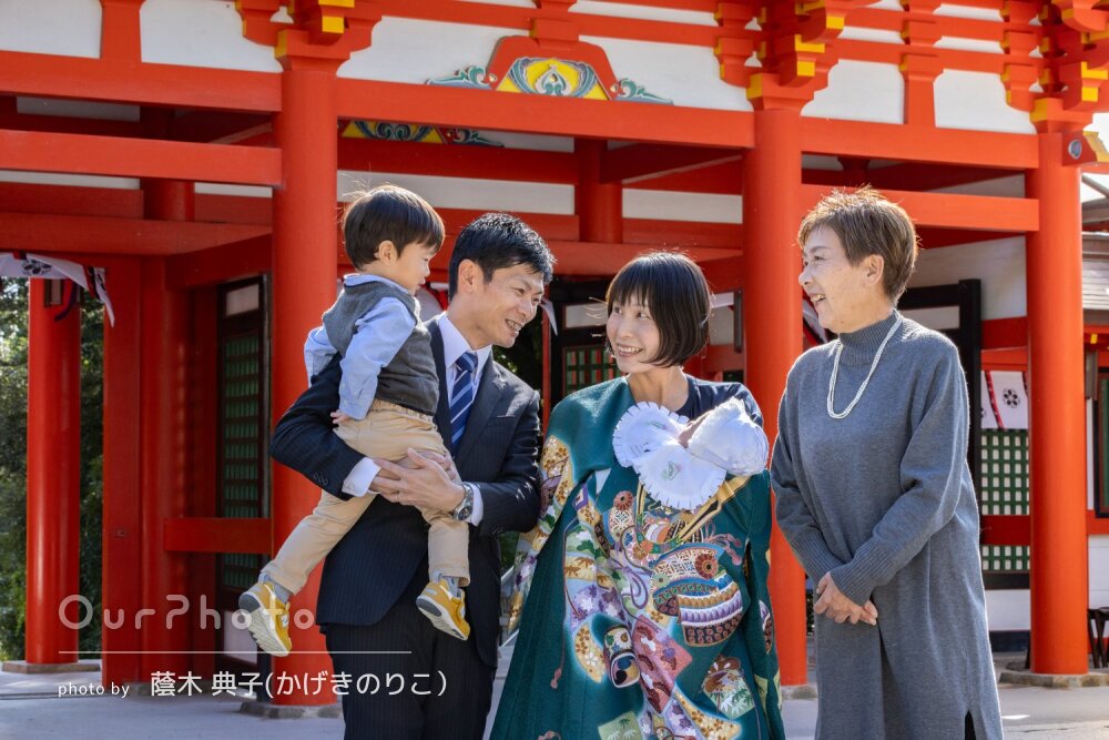 「笑顔の写真をたくさん」緑色の産着が朱色の社殿に映えるお宮参りの撮影